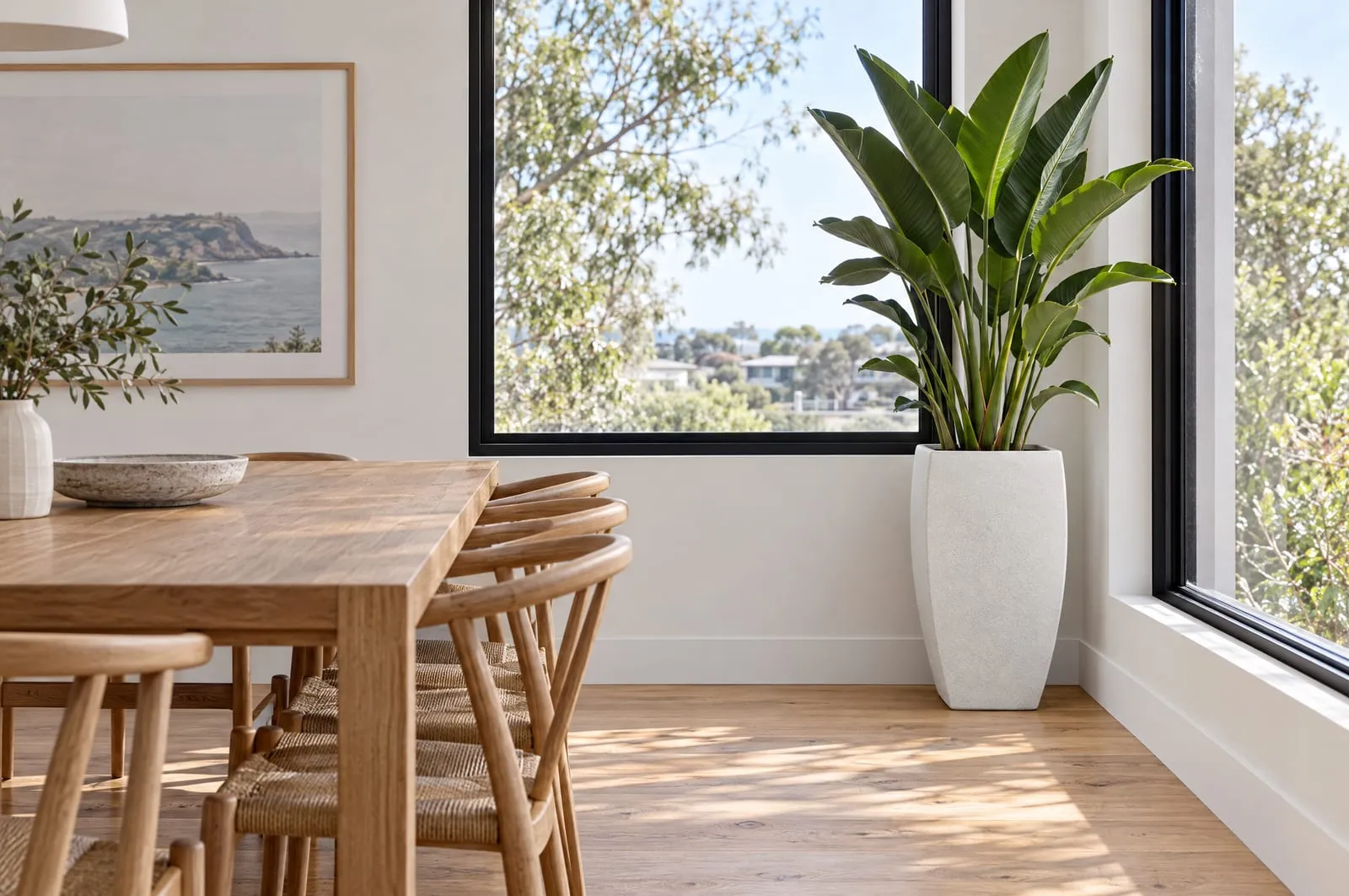 An Everleigh pot in Blizzard with a bird of paradise in the corner of a dining room